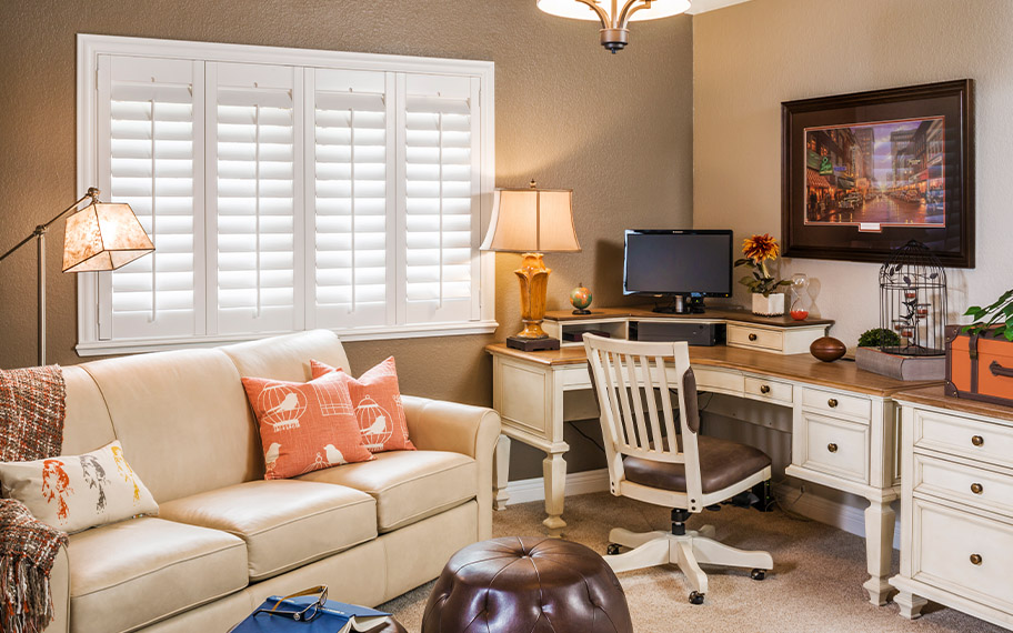 Polywood interior shutters are well-insulated against condensation. Photo Credit: Room Resolutions. White Polywood shutters in an office living room setting.